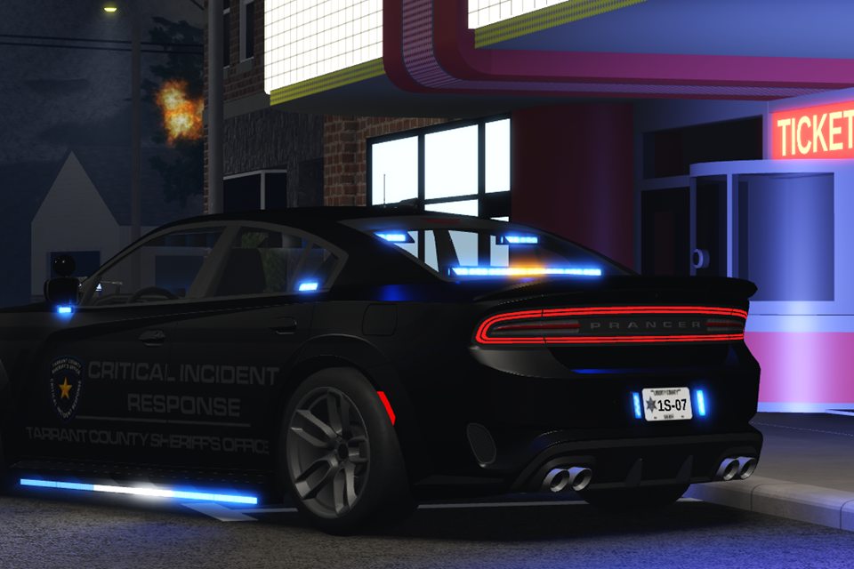 A black sheriff’s car of a critical incident response team parked outside a cinema at night