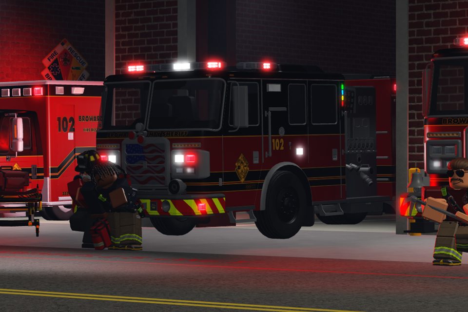 Firefighters outside their station, beside a fire engine and an ambulance